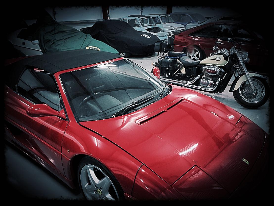 Inside our secure vehicle storage unit showcasing stored classic and sports cars along with a motorbike.