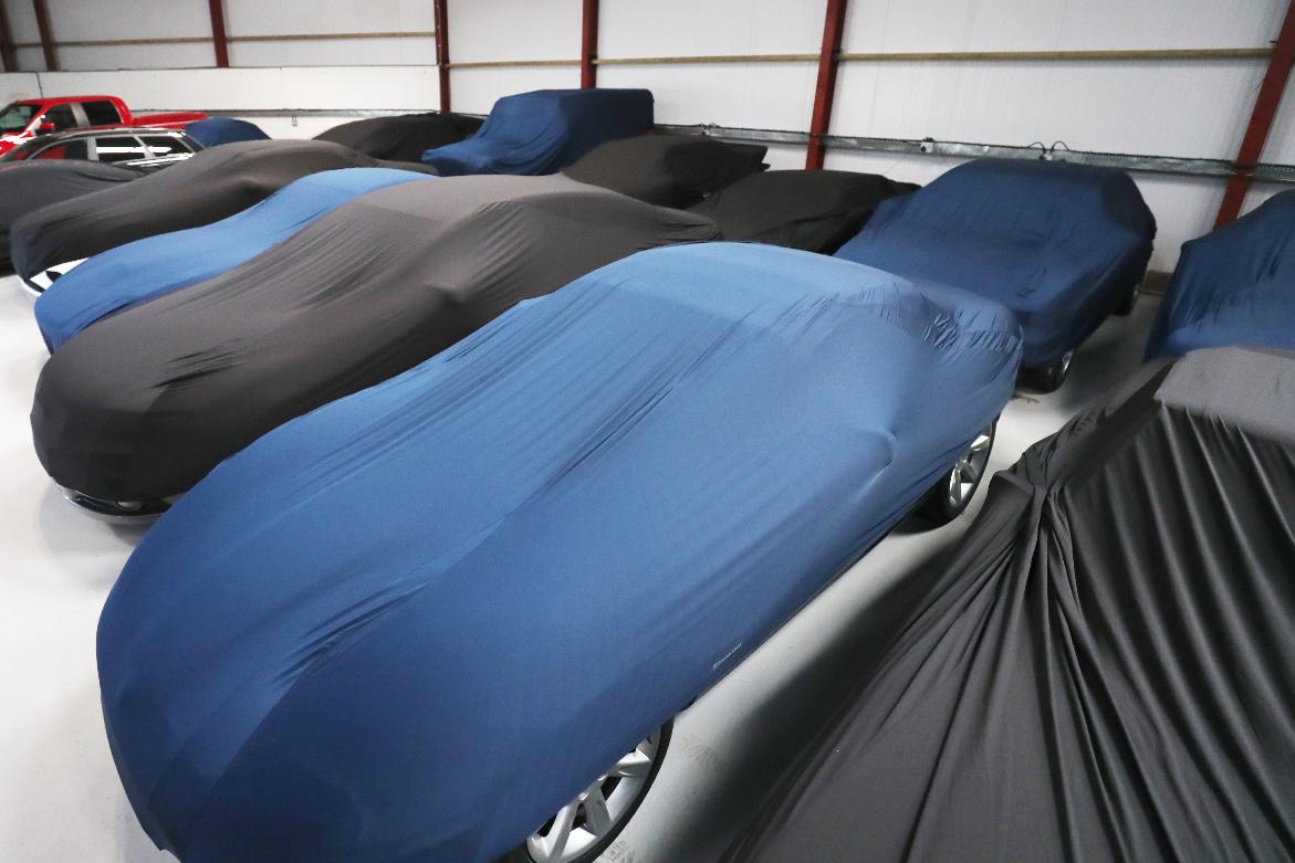 Presenting a number of luxury cars stored correctly inside a secure storage facility, all with dust covers for extra protection.